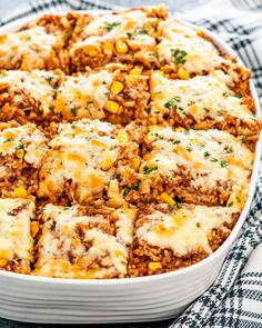 a casserole dish filled with ground beef, cheese and corn is shown on a checkered cloth