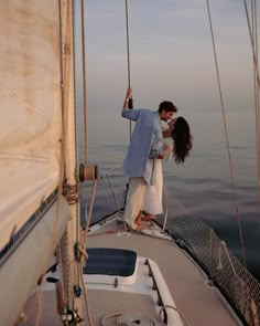 a man and woman kissing on the deck of a sailboat