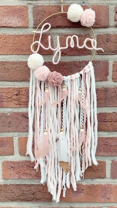 a pink and white dream catcher hanging on a brick wall