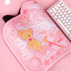 a pink mouse pad with an angel bear on it and a keyboard next to it