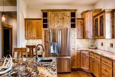 a kitchen with wooden cabinets and granite counter tops, stainless steel refrigerator and dishwasher