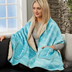 a woman sitting on a couch wearing a blue blanket