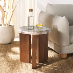 a table with a bottle and glass on it sitting in front of a white couch