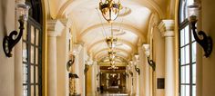 the hallway is lined with arched windows and chandeliers, along with marble flooring