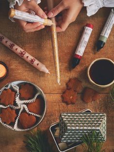 two people holding candles and some cookies on a table with other items around them,