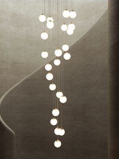 an artistic light fixture hanging from the side of a spiral staircase in a modern building