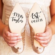 the bride is holding her wedding shoes with their names on them, and they are both wearing