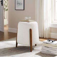 a white stool sitting on top of a wooden floor next to a pile of books