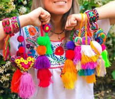 a woman wearing colorful bracelets and smiling at the camera with her hand on her hip