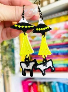 a pair of earrings with black and yellow designs hanging from it's ear wires