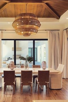 a dining room table with chairs and a chandelier hanging from it's ceiling