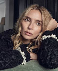 a woman with blonde hair and pearls on her arm