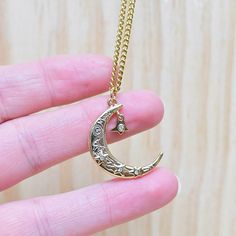 Looking for a celestial necklace with lots of magic and luck? This necklace is it! This necklace is made from a crescent moon charm. The moon charm has three stars with clear cz centers on the front. On the front of the moon the words; magic, luck and love can be seen along with a peace sign and an evil eye. A star drop hangs from the moon. The star like the others has a clear cz crystal in the center. The pendant is gold plated and has a shiny surface. The necklace is finished off with a stainl Half Moon Metal Necklace For Gifts, Half Moon Metal Necklace For Gift, Half Moon Brass Necklace For Gift, Crescent Moon Charm Necklace, Metal Moon Phase Charm Necklace As Gift, Brass Moon Charm Necklace For Gift, Engraved Moon-shaped Brass Necklace, Engraved Brass Moon Necklace, Engraved Moon Shaped Brass Necklace