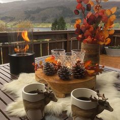 a table topped with cups and vases filled with pine cones