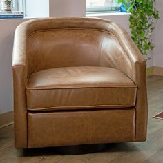 a brown leather chair sitting on top of a hard wood floor next to a window