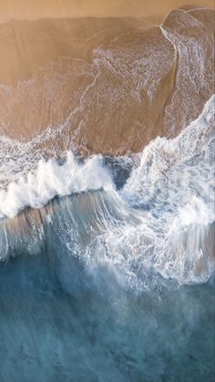 an aerial view of the ocean waves and sand