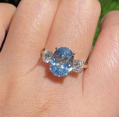 a woman's hand holding a blue and white diamond ring