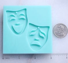 a penny sitting next to a plastic mold that looks like two masks on top of each other