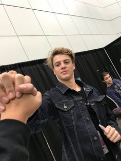 a young man holding his fist up in front of two other men who are standing next to each other