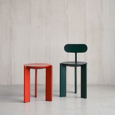 two different colored stools sitting next to each other in front of a white wall