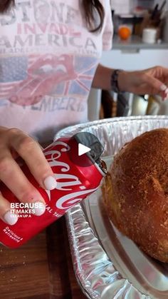 a woman is pouring soda into a loaf of bread on a plate with another person in the background