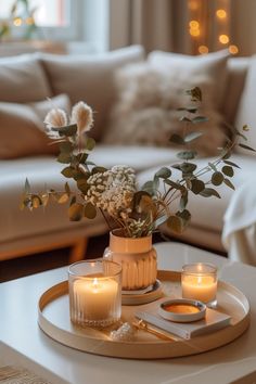 candles and flowers sit on a tray in front of a couch