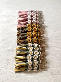 a bunch of different colored hair clips on a white surface with some flowers in the middle