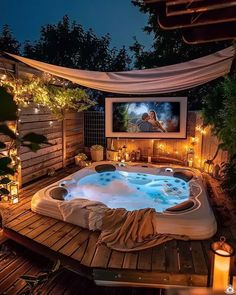 a hot tub in the middle of a wooden deck with lights around it and a screen on the wall