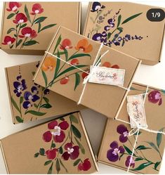 four brown boxes with colorful flowers painted on them and tied to each other in twine