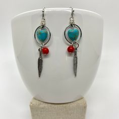 These look a little southwestern to me. I love turquoise, silver, and coral colors together. I grew up in South Dakota, so these remind me of home.  ♥ Materials used: - silver hoop earrings - turquoise magnesite heart beads - red coral howlite beads - silver feather charms ♥ CARING FOR YOUR JEWELRY Gently wipe your jewelry with a soft cloth to remove sweat, perfume, excess oils or dirt before putting them away. All of these products are handmade by me with care and attention to detail in a clean, smoke-free environment. I am happy to answer any questions you may have about any of my products. I also do custom orders, so please feel free to contact me with a design you have in mind. I will get back to you ASAP. Ships fast and free! Order today, ships next business day featuring USPS first c Red Bohemian Jewelry With Heart Charm, Handmade Bohemian Sterling Silver Heart Earrings, Bohemian Handmade Sterling Silver Heart Earrings, Bohemian Sterling Silver Heart Earrings, Chandelier Jewelry, Turquoise Heart Earrings, Coral Colors, Feather Earrings Silver, Home Materials