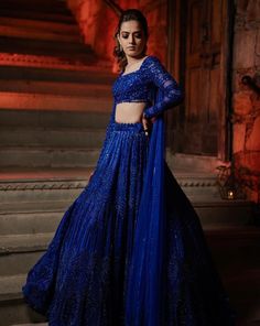 The lehenga features all over sequin, crystal, cutdana and crystal embroidery. Paired with a statement full sleeves blouse with dangling tassel detailing at the back and attached one shoulder drape.DELIVERY TIMEPlease allow 8-12 weeks for your outfit to arrive.FABRIC DETAILSNetProfessional cleaning only. Blue Fitted Sets With Unstitched Blouse, Fitted Blue Choli With Traditional Drape, Royal Blue Fitted Choli With Resham Embroidery, Fitted Royal Blue Choli With Resham Embroidery, Royal Blue Resham Embroidery Fitted Choli, Elegant Blue Fitted Lehenga, Elegant Fitted Blue Lehenga, Fitted Bollywood Sharara In Royal Blue, Fitted Bollywood Style Royal Blue Sharara