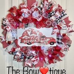 the bowtiqueve wreath is decorated with red and white ribbons, hearts, and bows