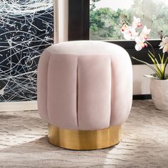 a pink and gold stool in front of a window