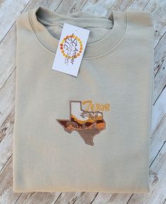 Texas state graphic embroidered on sweatshirt. Fall College T-shirt With Embroidered Graphics, Western Embroidered Sweatshirt, Fall College Embroidered T-shirt, Embroidered Fall College T-shirt, Embroidered Graphics T-shirt For College In Fall, Fall College T-shirt With Embroidered Logo, College T-shirt With Embroidered Logo For Fall, Embroidered Text T-shirt For College In Fall, Embroidered Patch Tops For Streetwear In Fall