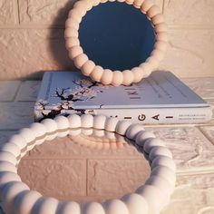 a book sitting on top of a table next to a white ring with a mirror