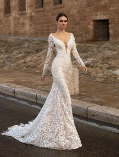 a woman in a wedding dress is standing on the street near an old brick building