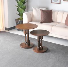 two wooden tables sitting on top of a carpeted floor next to a white couch