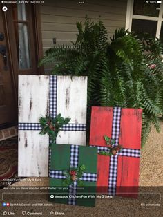 three wooden blocks decorated with plaid and holly wreaths are sitting on the front porch