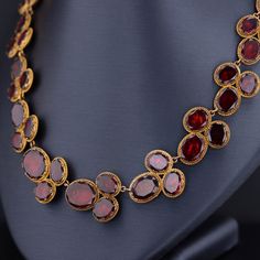 Experience the timeless elegance of this remarkable antique necklace dating back to the late Georgian era (circa 1820). Crafted with meticulous artistry, this exquisite piece showcases 54 oval flat-cut, foil backed garnets, set in 14k bloomed gold with closed backs, preserving their radiance for centuries. Measuring 16 inches in length, this antique necklace exudes a captivating charm and is in overall good condition. While there is one visible surface-reaching inclusion, it adds to the characte Opulent Formal Necklaces With 17 Jewels, Oval Jewelry With 17 Jewels For Evening, Opulent Round Necklaces For Formal Occasions, Classic Evening Ruby Jewelry, Luxury Oval Jeweled Necklaces, Luxury Jeweled Oval Necklaces, Victorian Ruby Necklace For Formal Occasions, Victorian Oval Jewelry For Opera, Antique Ruby Necklace For Formal Occasions