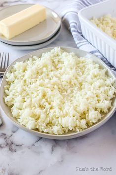 a plate with rice and butter on it next to silverware, forks and spoons