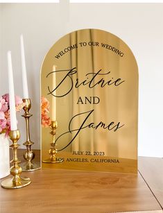 a gold arch with the words, welcome to our wedding on it next to candles and flowers