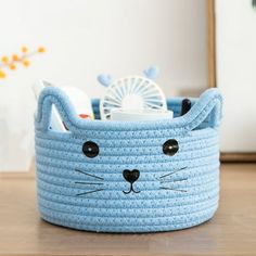 a blue cat basket sitting on top of a wooden table