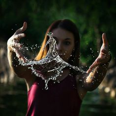 a woman holding up her hands with water coming out of it