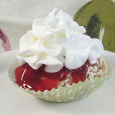 a white plate topped with a cupcake covered in whipped cream