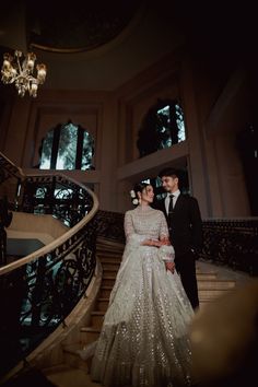 a bride and groom standing in front of a staircase