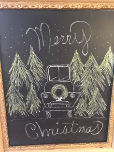 a chalk board with the words merry christmas written on it in front of pine trees