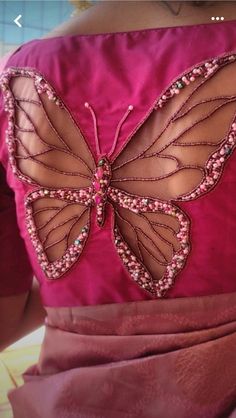 the back of a woman's pink dress with a butterfly appliqued on it