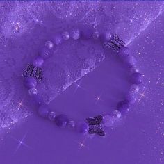 a purple beaded bracelet with two butterflies on it and sparkles in the background