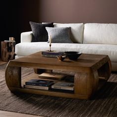 a coffee table sitting on top of a rug in front of a white couch next to a book shelf