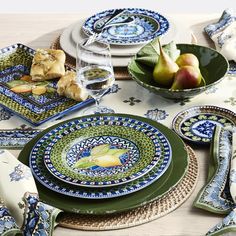 a table set with plates, napkins and fruit